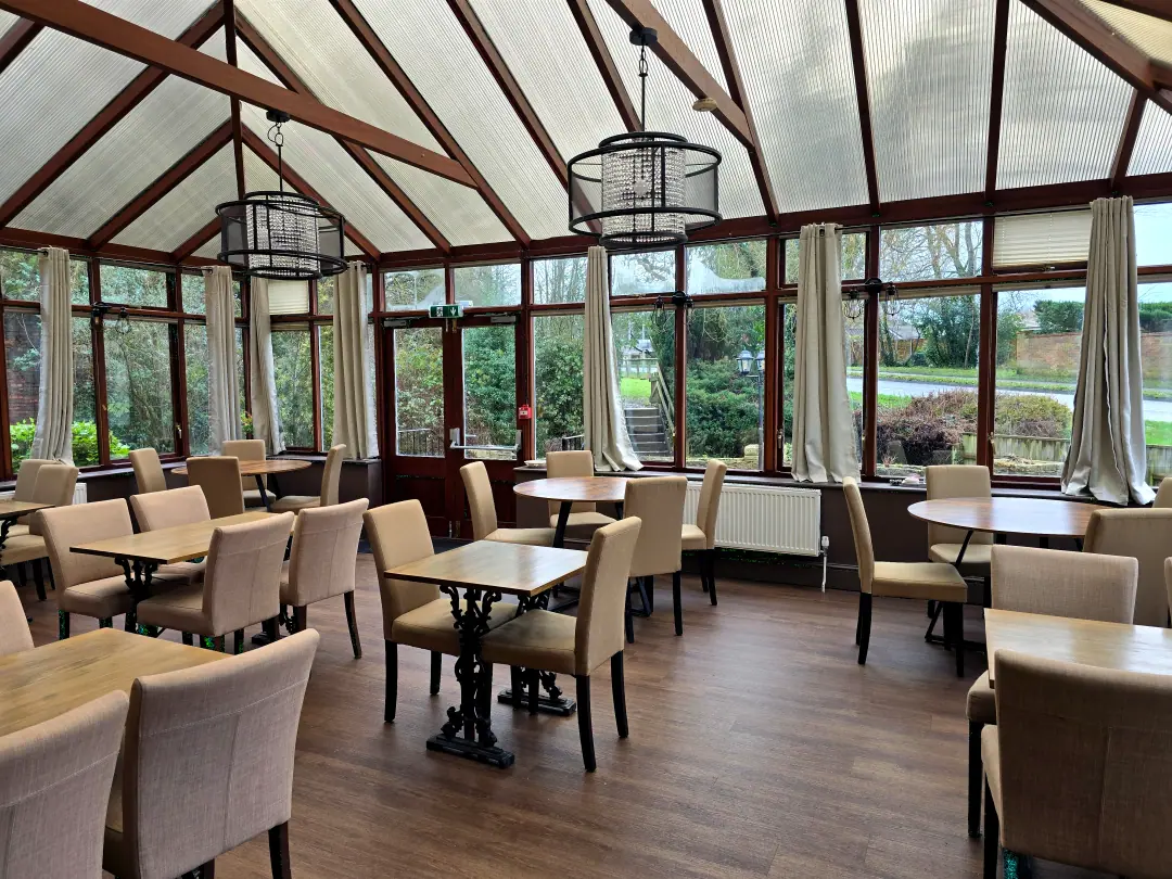 The conservatory with a timber-framed glass roof, crystal pendant lights and garden views