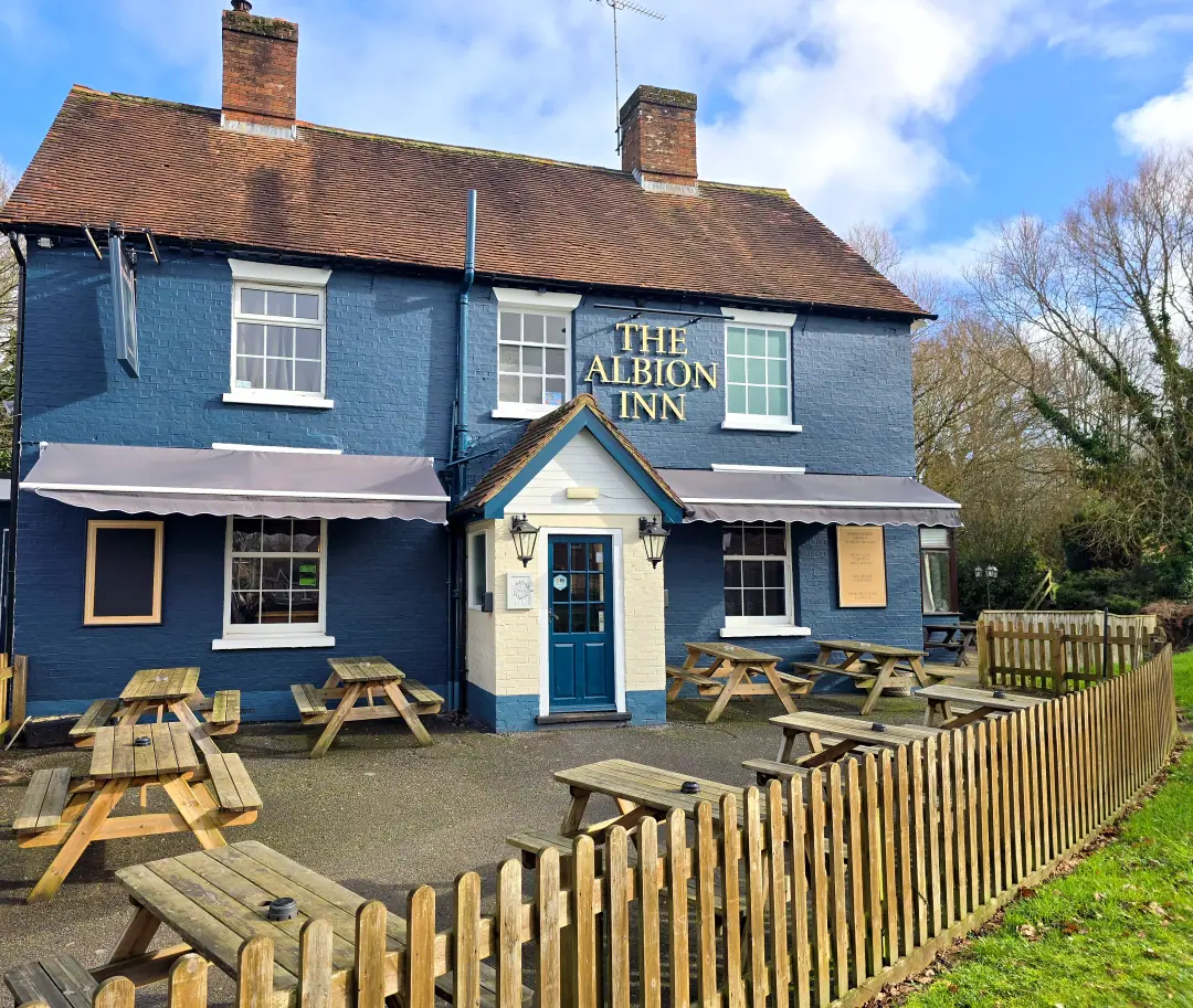 The front of the Albion Inn: navy-painted brick, gilt lettering and picnic benches under a blue sky