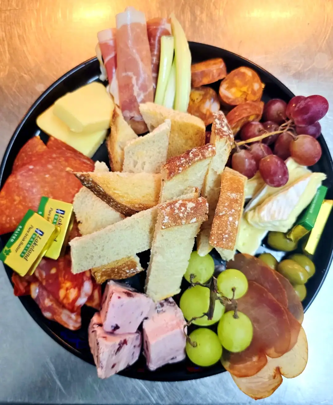 A sharing board of cured meats, cheeses, bread and grapes